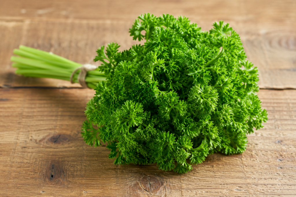 Fresh parsley bunch beside a green juice on a sunlit counter, illustrating apigenin and bladder cancer research